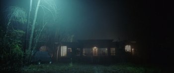 Movie still from “Manhunter” (1986), directed by Michael Mann – A house in the dark at night with lights on; Extreme Wide shot, Low angle