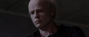 Movie still from “Manhunter” (1986), directed by Michael Mann – A man with a bald head is looking at the camera; Close Up shot, Low angle