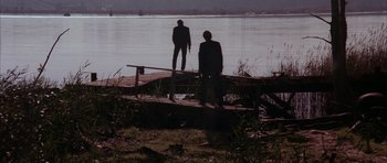 Movie still from “Manhunter” (1986), directed by Michael Mann – Two men standing on a dock looking out at the water; Extreme Wide shot, Low angle