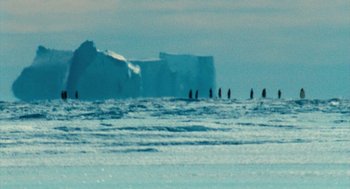 Movie still from “March of the Penguins” (2005), directed by Luc Jacquet – A group of people standing on top of a body of water; Extreme Wide shot, Over the shoulder angle