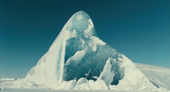 Movie still from “March of the Penguins” (2005), directed by Luc Jacquet – A large piece of ice sitting on top of a snow covered slope; Extreme Wide shot, High angle