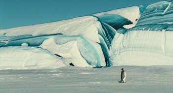Movie still from “March of the Penguins” (2005), directed by Luc Jacquet – A penguin standing on top of a snow covered slope; Extreme Wide shot, Low angle