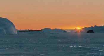 Movie still from “March of the Penguins” (2005), directed by Luc Jacquet – The sun is setting over a frozen lake; Extreme Wide shot, Low angle