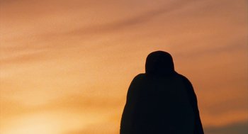 Movie still from “March of the Penguins” (2005), directed by Luc Jacquet – A person standing in front of an orange sky; Extreme Close Up shot, Low angle