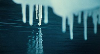 Movie still from “March of the Penguins” (2005), directed by Luc Jacquet – The water is reflecting the sky with icicles on it's surface; Extreme Close Up shot, Low angle