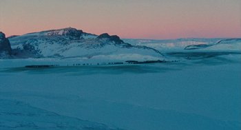 Movie still from “March of the Penguins” (2005), directed by Luc Jacquet – A view of a snowy mountain range at dusk; Extreme Wide shot, High angle