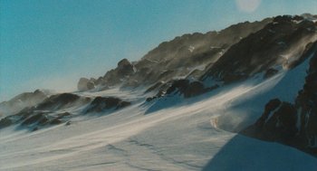 Movie still from “March of the Penguins” (2005), directed by Luc Jacquet – A snowy hill with a mountain in the background; Extreme Wide shot, High angle