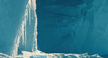 Movie still from “March of the Penguins” (2005), directed by Luc Jacquet – A person standing on top of a snow covered slope; Extreme Wide shot, Low angle