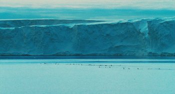 Movie still from “March of the Penguins” (2005), directed by Luc Jacquet – A large body of water near a mountain range; Extreme Wide shot, High angle