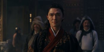 Movie still from “Marco Polo” (2014), created by John Fusco – A man wearing a black and red robe and a red tie; Close Up shot, Low angle