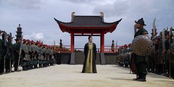Movie still from “Marco Polo” (2014), created by John Fusco – A man dressed in a costume stands in front of a group of people; Extreme Wide shot, Low angle