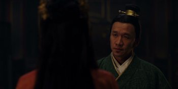 Movie still from “Marco Polo” (2014), created by John Fusco – A man wearing a green and gold outfit looking at himself in the mirror; Close Up shot, Over the shoulder angle