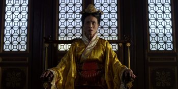 Movie still from “Marco Polo” (2014), created by John Fusco – An older woman in a yellow outfit sitting in a chair; Medium shot, Low angle