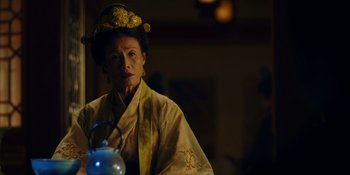 Movie still from “Marco Polo” (2014), created by John Fusco – An older woman wearing a yellow robe and a gold hat; Medium shot, Low angle