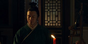 Movie still from “Marco Polo” (2014), created by John Fusco – A man in a green robe holding a candle; Medium shot, Low angle
