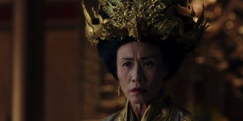 Movie still from “Marco Polo” (2014), created by John Fusco – An older woman wearing a gold headdress and looking sad; Close Up shot, Over the shoulder angle