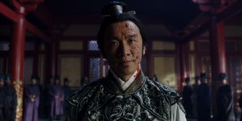 Movie still from “Marco Polo” (2014), created by John Fusco – A man in a traditional chinese costume with a hat on his head; Close Up shot, Low angle
