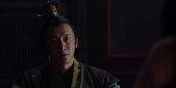 Movie still from “Marco Polo” (2014), created by John Fusco – A man wearing a robe and a hat in a dark room; Close Up shot, Low angle