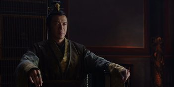 Movie still from “Marco Polo” (2014), created by John Fusco – A man wearing a robe and a hat is posing for a picture; Medium shot, Low angle