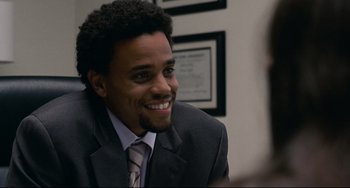Movie still from “Margaret” (2011), directed by Kenneth Lonergan – A man wearing a suit and tie smiling for the camera; Close Up shot, Over the shoulder angle