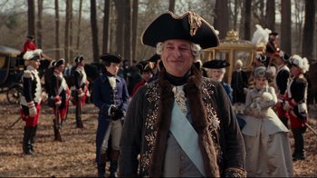 Movie still from “Marie Antoinette” (2006), directed by Sofia Coppola – An old man in a hat and a fur coat standing in front of a group of people; Medium shot, Over the shoulder angle