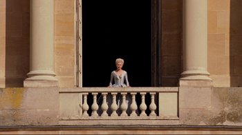 Movie still from “Marie Antoinette” (2006), directed by Sofia Coppola – A woman dressed as a princess sitting on a balcony; Wide shot, Low angle