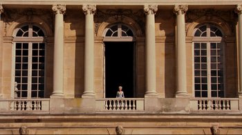 Movie still from “Marie Antoinette” (2006), directed by Sofia Coppola – A woman standing on a balcony looking out of a window; Extreme Wide shot, Low angle