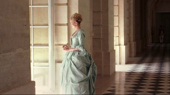 Movie still from “Marie Antoinette” (2006), directed by Sofia Coppola – A woman dressed in a green dress standing in a room; Wide shot, Over the shoulder angle