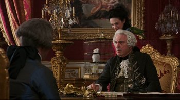 Movie still from “Marie Antoinette” (2006), directed by Sofia Coppola – An older man and a young woman sitting at a table; Medium shot, Over the shoulder angle