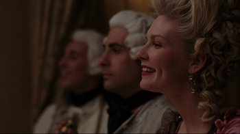 Movie still from “Marie Antoinette” (2006), directed by Sofia Coppola – Three people in historical dress smiling for the camera; Close Up shot, Over the shoulder angle