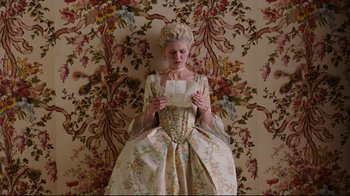 Movie still from “Marie Antoinette” (2006), directed by Sofia Coppola – A woman dressed in period dress reading a piece of paper; Medium shot, Overhead angle