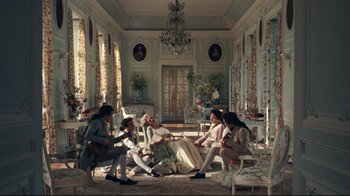Movie still from “Marie Antoinette” (2006), directed by Sofia Coppola – A group of people sitting on top of couches in a living room; Wide shot, Overhead angle