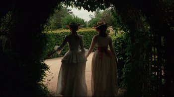 Movie still from “Marie Antoinette” (2006), directed by Sofia Coppola – Two women dressed in period clothing walking through a garden; Medium shot, Low angle