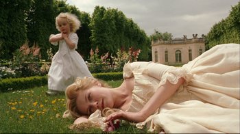 Movie still from “Marie Antoinette” (2006), directed by Sofia Coppola – A woman laying in the grass next to a little girl; Wide shot, High angle