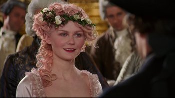 Movie still from “Marie Antoinette” (2006), directed by Sofia Coppola – A woman in a pink dress with flowers in her hair; Close Up shot, Over the shoulder angle