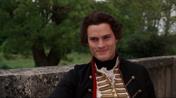 Movie still from “Marie Antoinette” (2006), directed by Sofia Coppola – A young man in a military uniform smiling for the camera; Close Up shot, Over the shoulder angle