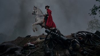 Movie still from “Marie Antoinette” (2006), directed by Sofia Coppola – A man riding on the back of a white horse next to a cannon; Wide shot, Low angle
