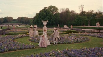 Movie still from “Marie Antoinette” (2006), directed by Sofia Coppola – A group of people dressed in period costumes in a garden; Extreme Wide shot, High angle