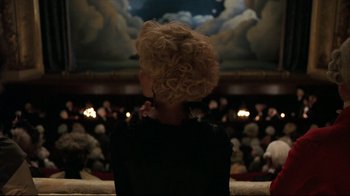 Movie still from “Marie Antoinette” (2006), directed by Sofia Coppola – A woman sitting in front of an audience in a theater; Medium shot, Low angle