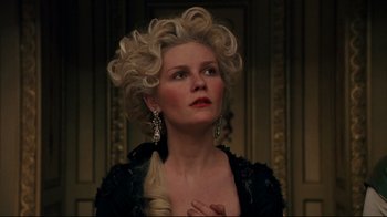 Movie still from “Marie Antoinette” (2006), directed by Sofia Coppola – A woman with blonde curly hair wearing a black jacket; Close Up shot, Low angle