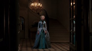 Movie still from “Marie Antoinette” (2006), directed by Sofia Coppola – A woman in a blue dress standing in front of a staircase; Wide shot, Low angle