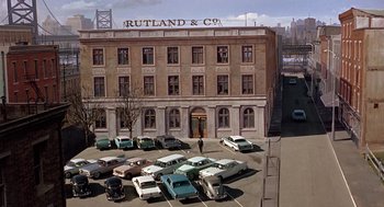 Movie still from “Marnie” (1964), directed by Alfred Hitchcock – An old photo of cars parked in front of a building; Extreme Wide shot, High angle