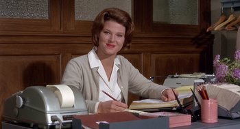 Movie still from “Marnie” (1964), directed by Alfred Hitchcock – A woman sitting at a desk writing on a piece of paper; Medium shot, Low angle
