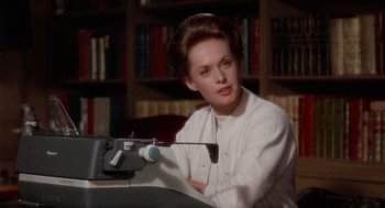 Movie still from “Marnie” (1964), directed by Alfred Hitchcock – A woman sitting in front of a typewriter in front of a bookshelf; Close Up shot, High angle