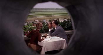 Movie still from “Marnie” (1964), directed by Alfred Hitchcock – A man and a woman sitting at an outdoor table; Medium shot, High angle