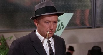 Movie still from “Marnie” (1964), directed by Alfred Hitchcock – A man in a suit and hat smoking a pipe; Close Up shot, Low angle