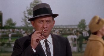 Movie still from “Marnie” (1964), directed by Alfred Hitchcock – A man in a suit and hat smoking a cigarette; Close Up shot, Over the shoulder angle