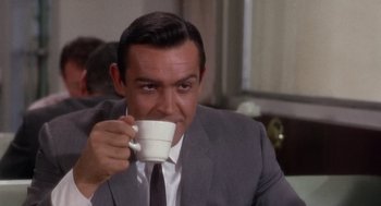 Movie still from “Marnie” (1964), directed by Alfred Hitchcock – A man in a suit and tie holding a coffee cup; Close Up shot, Over the shoulder angle