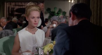 Movie still from “Marnie” (1964), directed by Alfred Hitchcock – A woman sitting at a dinner table with a man; Medium shot, Over the shoulder angle