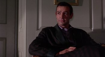 Movie still from “Marnie” (1964), directed by Alfred Hitchcock – A man sitting in a chair with his arms crossed; Medium shot, Low angle